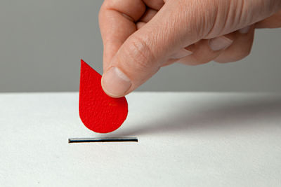 This is a picture of someone holding a cut out of a blood drop lowering it down to a black line