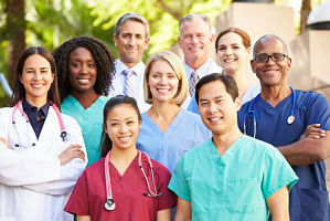 A group of male and female doctors and nurses standing together and smiling for a picture