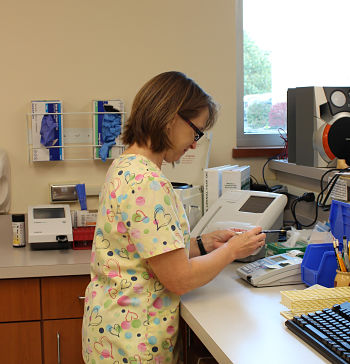A female nurse standing beside a counter holding a pencil