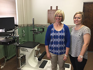 Two women standing in an examination room smiling for a photo