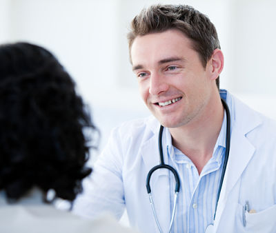 A medical professional smiling and speaking with a female whose face we cannot see