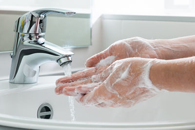 Two hands covered in soap being washed in the sink