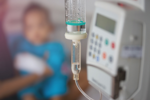 A photo of an IV tube with the blurred image of a baby in the background