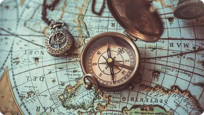 An antique compass sitting on top of a world map