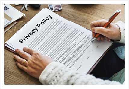 A stack of Privacy Policy papers sitting on a desk with a person writing on the paper