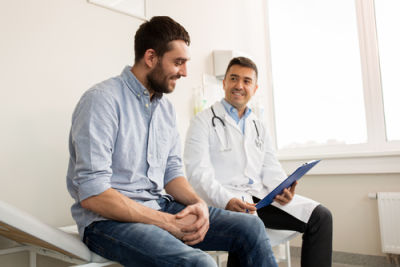 Picture of male doctor speaking with a male patient in an office setting.