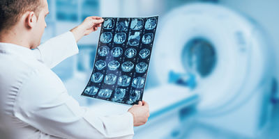 Picture of radiologist looking at scans with a MRI machine in the background.