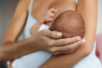 Picture of a mother cradling her babies head to breastfeed.